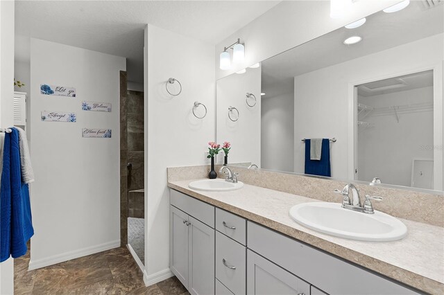 bathroom with a tile shower and vanity