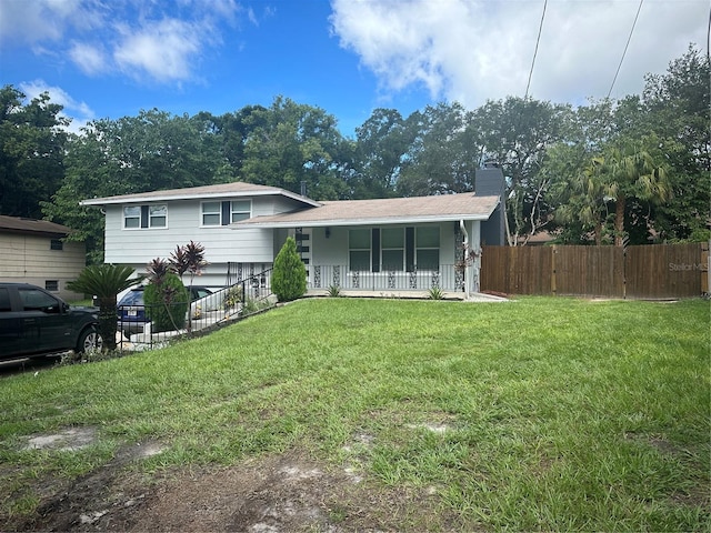 rear view of property featuring covered porch and a lawn