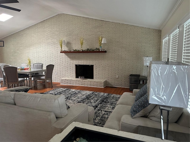 living room featuring lofted ceiling, hardwood / wood-style flooring, a fireplace, and crown molding