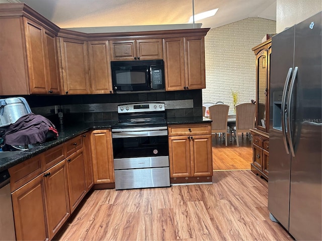 2524 Good Homes Rd, Orlando, FL 32818 - kitchen with appliances with stainless steel finishes, vaulted ceiling, light wood finished floors, backsplash, and brown cabinetry