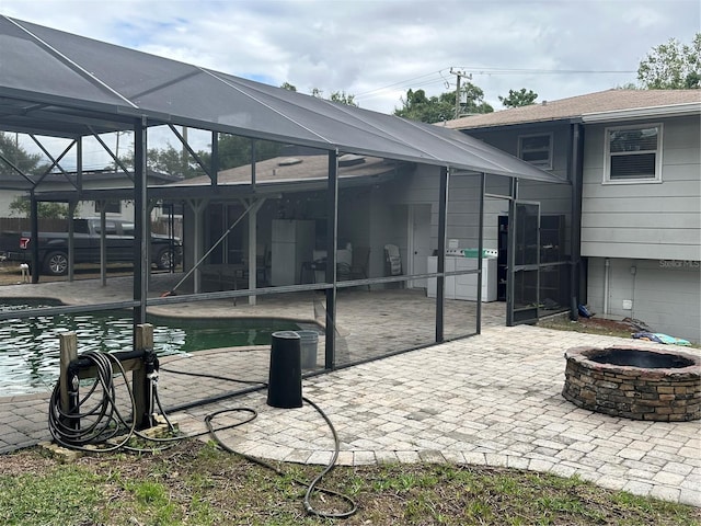 view of patio / terrace featuring an outdoor fire pit and glass enclosure