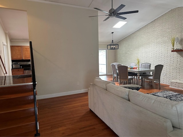 living room featuring brick wall, ceiling fan, lofted ceiling with skylight, and dark hardwood / wood-style flooring