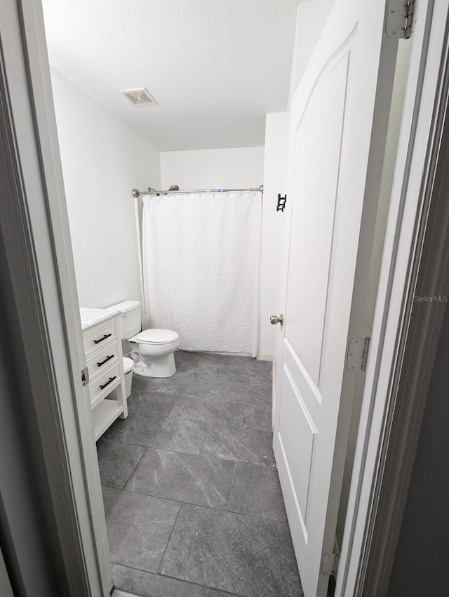 bathroom featuring vanity, tile patterned floors, and toilet