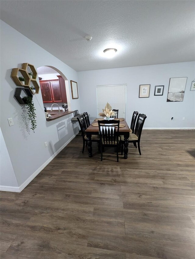 dining room with dark wood-type flooring and a textured ceiling