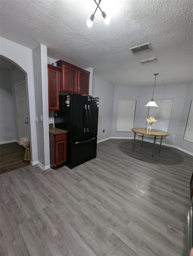 kitchen with black refrigerator, a textured ceiling, light hardwood / wood-style floors, and decorative light fixtures