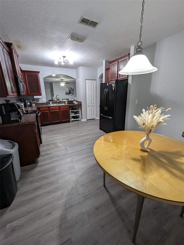 kitchen featuring light hardwood / wood-style flooring, black fridge, sink, and a textured ceiling