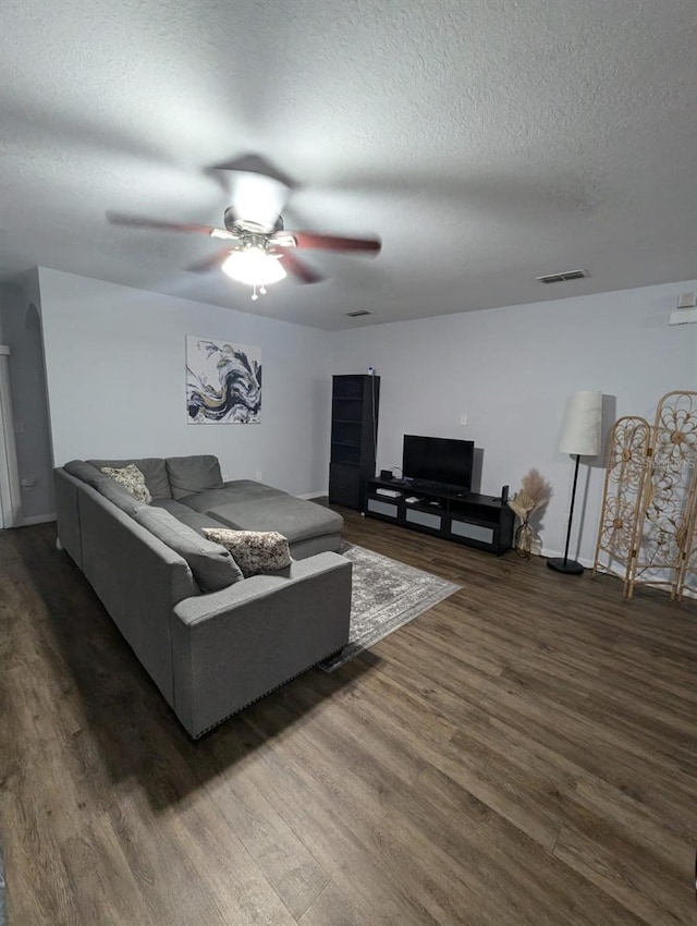 living room featuring a textured ceiling, dark hardwood / wood-style flooring, and ceiling fan