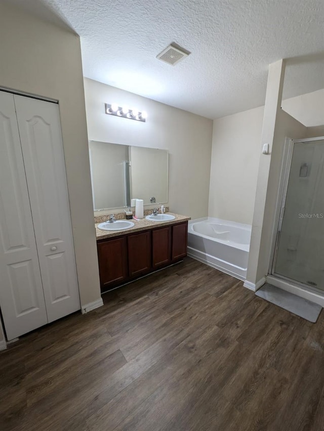 bathroom featuring double vanity, wood-type flooring, a textured ceiling, and independent shower and bath