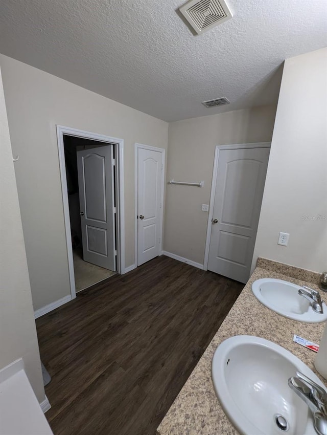 bathroom featuring dual vanity, a textured ceiling, and hardwood / wood-style flooring