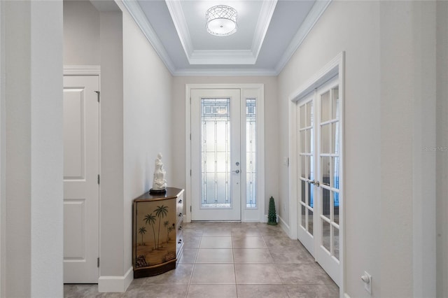 tiled entrance foyer featuring crown molding, a raised ceiling, and french doors