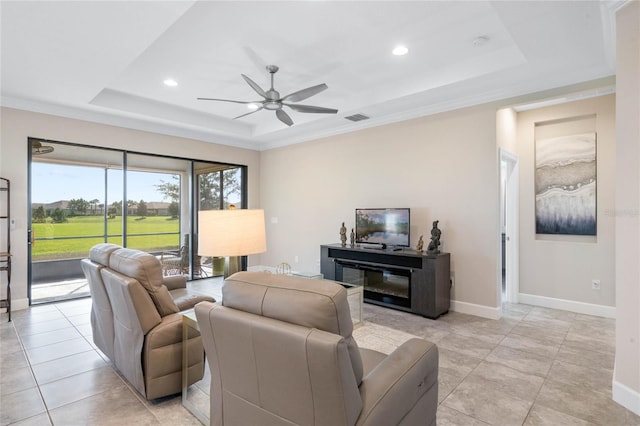 tiled living room with ceiling fan, a raised ceiling, and ornamental molding