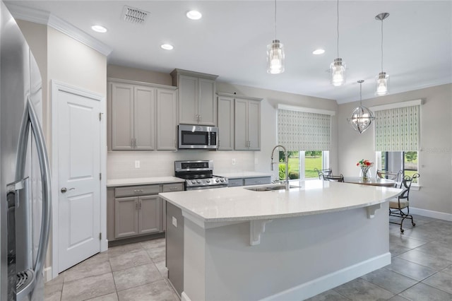 kitchen with appliances with stainless steel finishes, decorative backsplash, sink, a kitchen island with sink, and light tile patterned floors