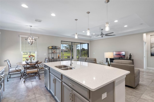 kitchen with a kitchen island with sink, decorative light fixtures, a tray ceiling, and dishwasher