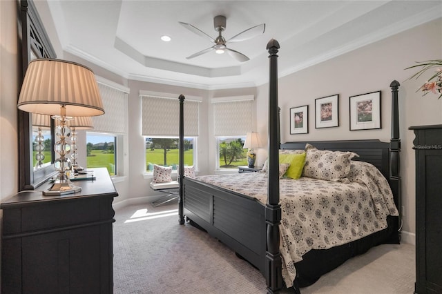 bedroom with ceiling fan, light carpet, crown molding, and a tray ceiling