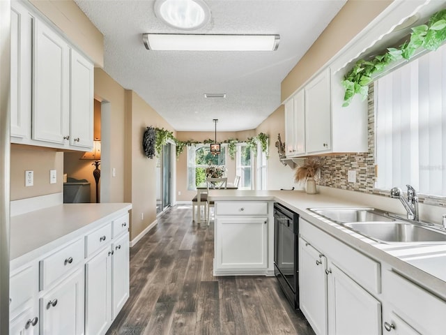 kitchen with white cabinets, black dishwasher, a sink, and a peninsula