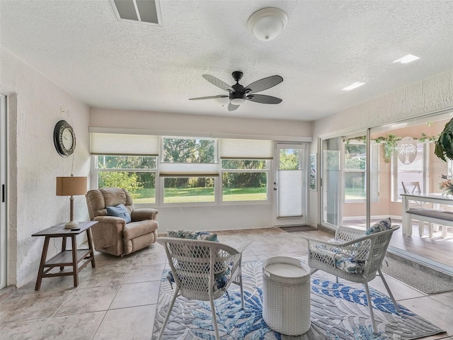 sunroom / solarium with visible vents, a textured wall, and tile patterned flooring