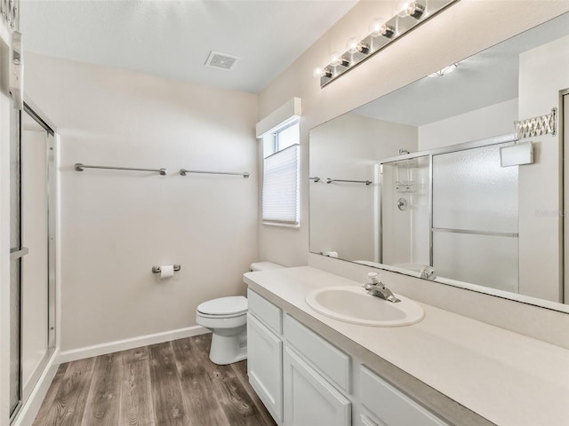 bathroom with wood-type flooring, vanity, a shower with door, and toilet