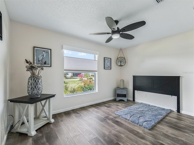 interior space featuring baseboards, a textured ceiling, wood finished floors, and ceiling fan