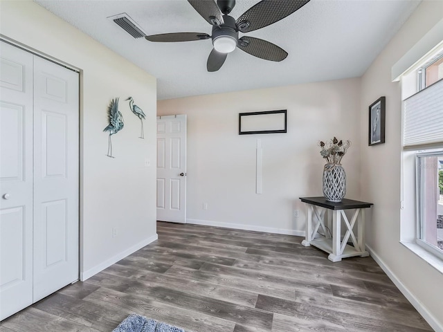 unfurnished bedroom featuring a closet, visible vents, baseboards, ceiling fan, and wood finished floors