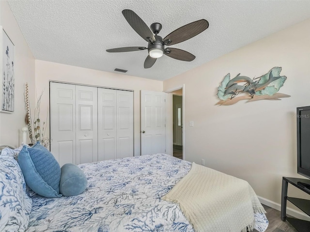 bedroom with a closet, a ceiling fan, a textured ceiling, baseboards, and visible vents