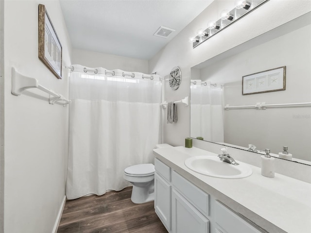 bathroom featuring visible vents, a shower with shower curtain, toilet, wood finished floors, and vanity