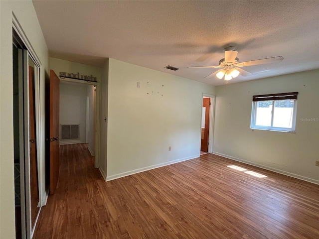 empty room with ceiling fan, wood-type flooring, and a textured ceiling