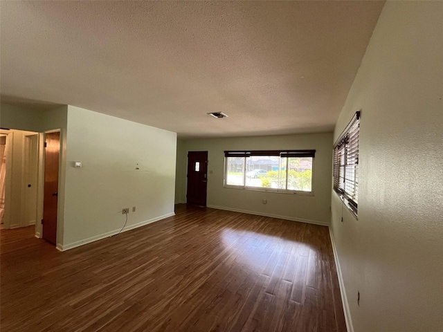 empty room with dark hardwood / wood-style flooring and a textured ceiling