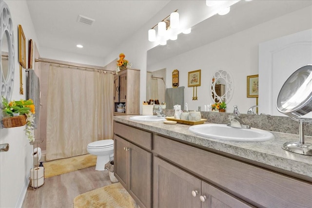 bathroom with double sink vanity, toilet, and hardwood / wood-style floors