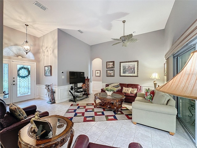 living room featuring high vaulted ceiling, ceiling fan with notable chandelier, and light tile patterned floors