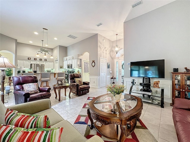 tiled living room with a towering ceiling and an inviting chandelier