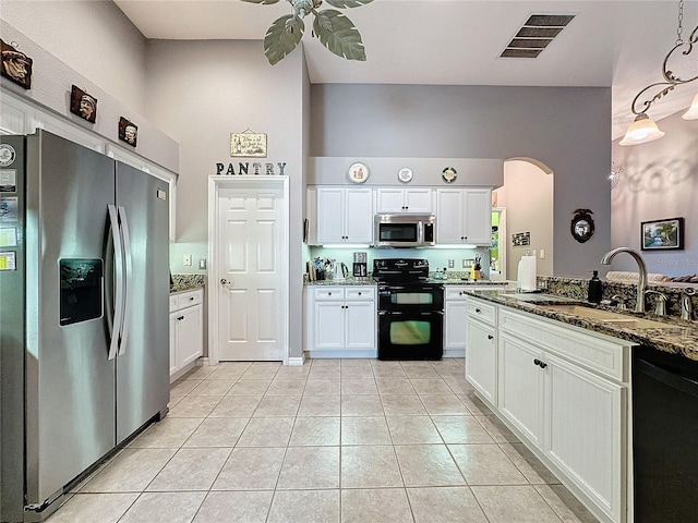 kitchen featuring dark stone counters, white cabinets, black appliances, light tile patterned floors, and sink