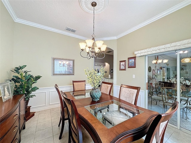 tiled dining room featuring a chandelier, a textured ceiling, and crown molding