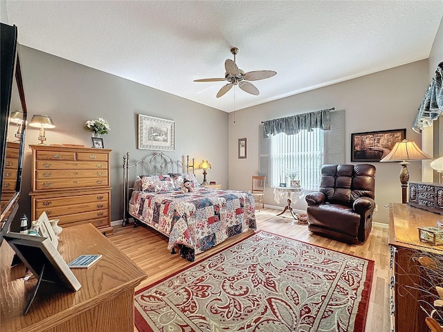 bedroom featuring ceiling fan, light hardwood / wood-style flooring, and a textured ceiling