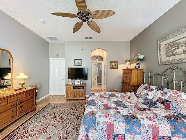 bedroom with ceiling fan, light wood-type flooring, and a textured ceiling