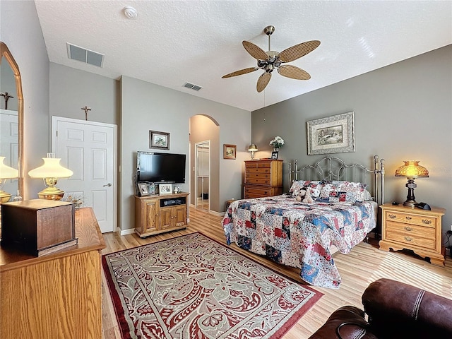 bedroom with ceiling fan, light hardwood / wood-style flooring, and a textured ceiling