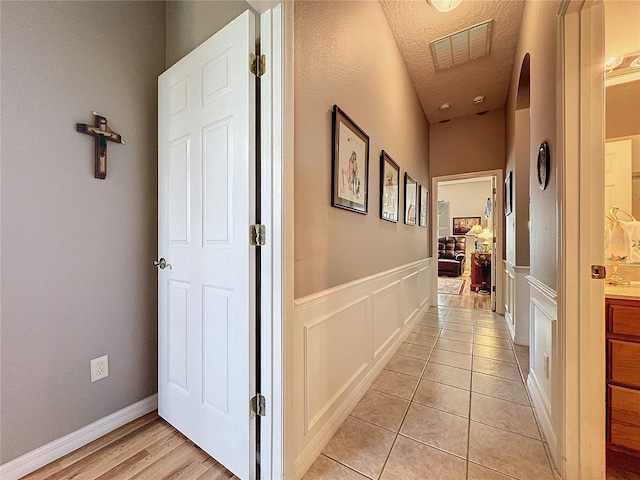 hall with light hardwood / wood-style flooring and a textured ceiling