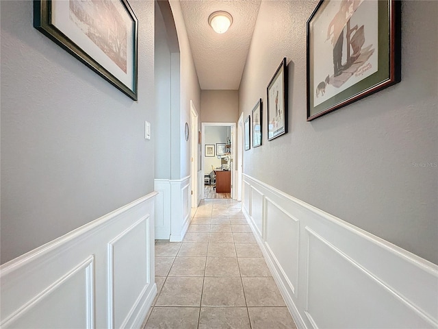 corridor with a textured ceiling and light tile patterned floors