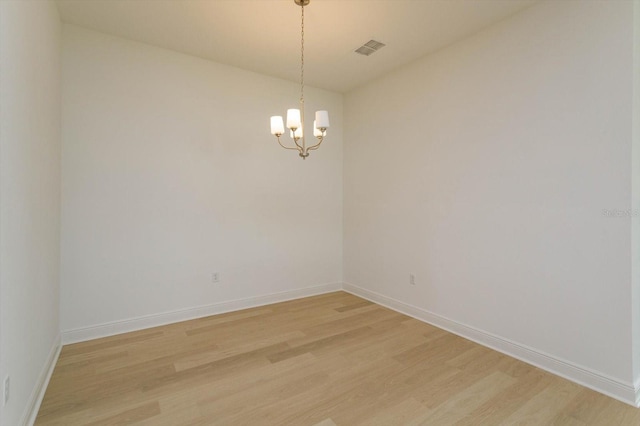 unfurnished room with an inviting chandelier and light hardwood / wood-style flooring