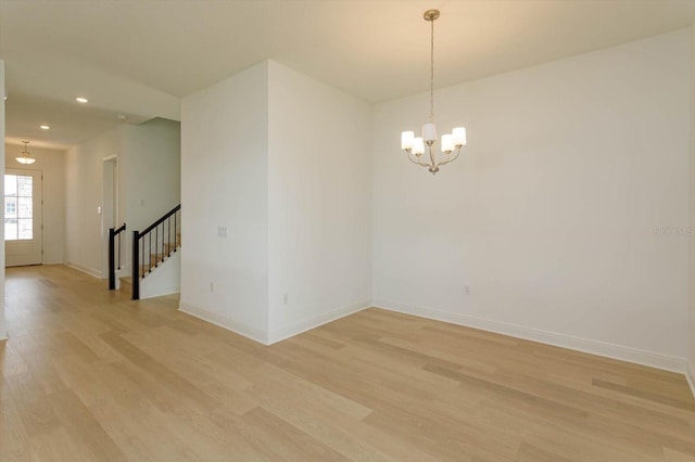 spare room with light hardwood / wood-style flooring and a chandelier