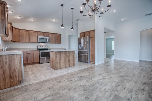 kitchen featuring light wood-type flooring, stainless steel appliances, decorative light fixtures, an inviting chandelier, and a kitchen island