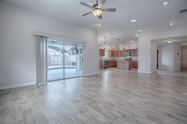 unfurnished living room featuring ceiling fan with notable chandelier and light hardwood / wood-style flooring