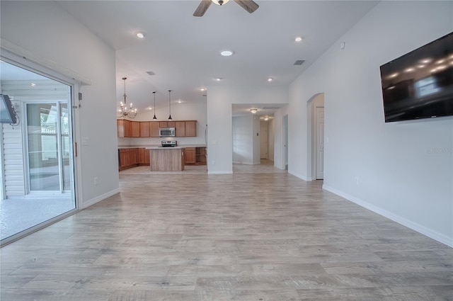 unfurnished living room featuring ceiling fan with notable chandelier and light hardwood / wood-style floors