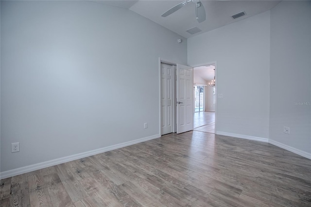 unfurnished room with ceiling fan with notable chandelier, lofted ceiling, and light wood-type flooring