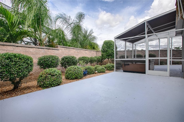 view of patio with a lanai and a hot tub