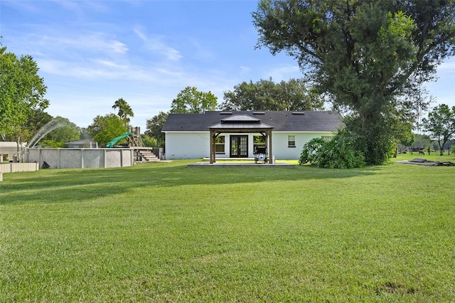 rear view of house with a gazebo, a yard, and a playground