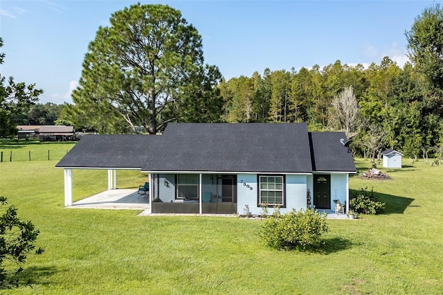 rear view of property with a yard, a patio area, and a storage unit