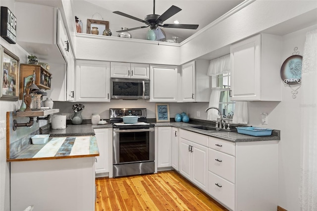 kitchen featuring white cabinetry, sink, ceiling fan, light hardwood / wood-style floors, and stainless steel appliances