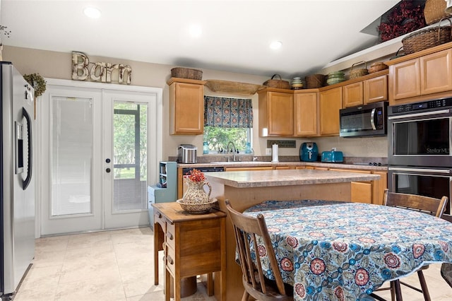 kitchen featuring french doors, sink, light tile patterned floors, a kitchen island, and stainless steel appliances