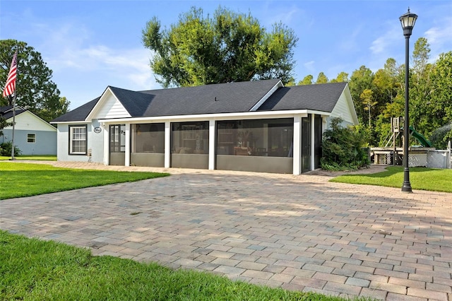 ranch-style home featuring a playground, a sunroom, and a front lawn