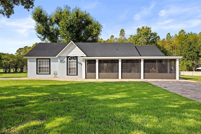 ranch-style home with a sunroom, driveway, and a front lawn